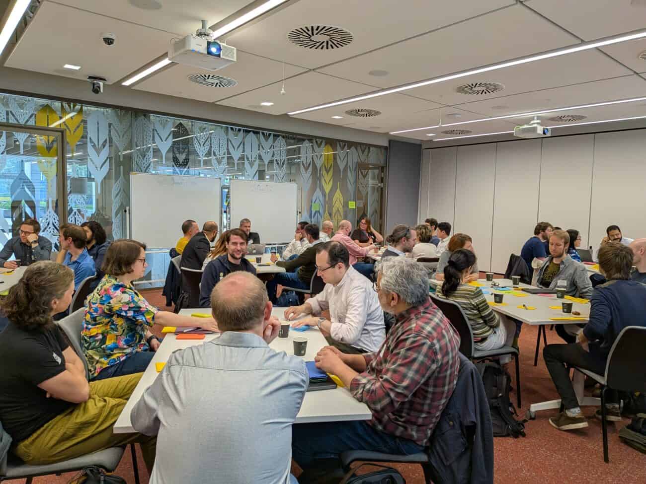 Co³ Academy participants seated together at a workshop table, engaged in discussion.